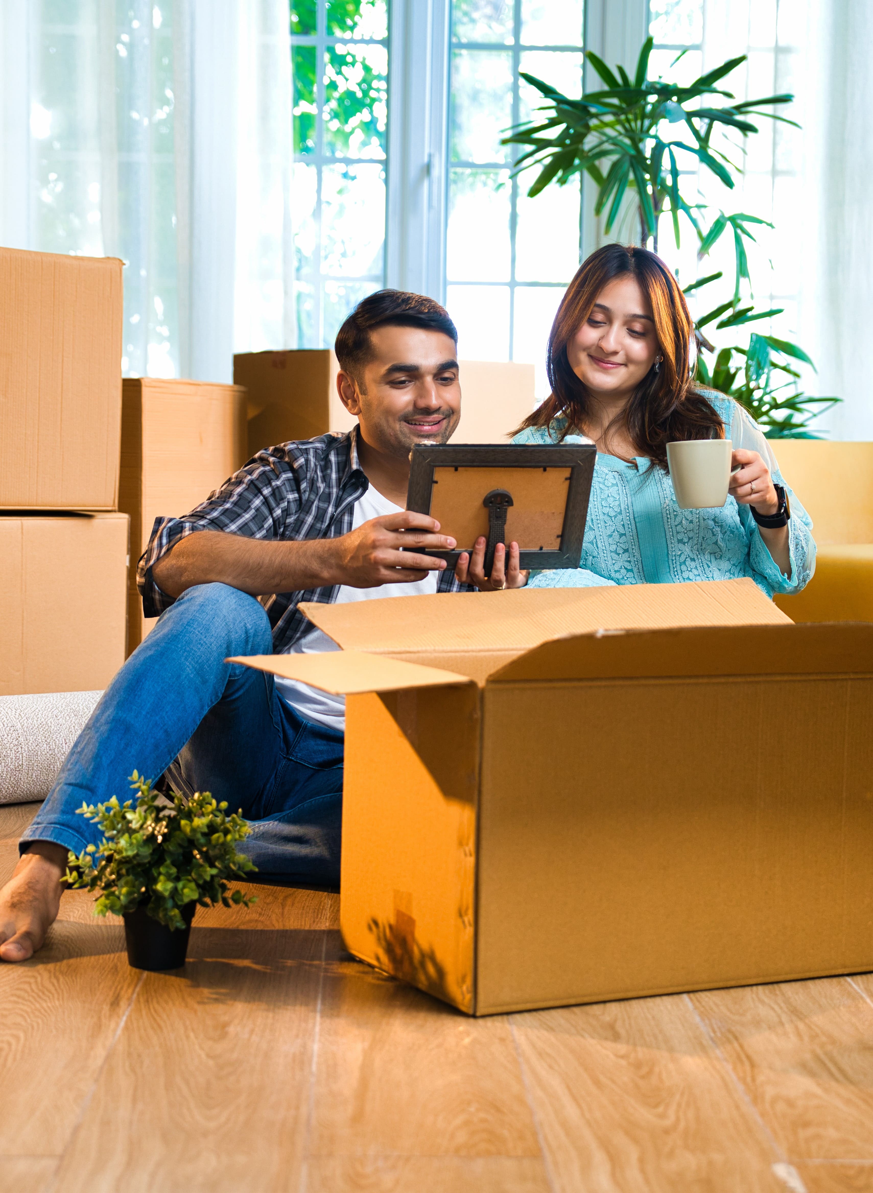 Smiling couple unpacking boxes in their new home while looking at a photo frame