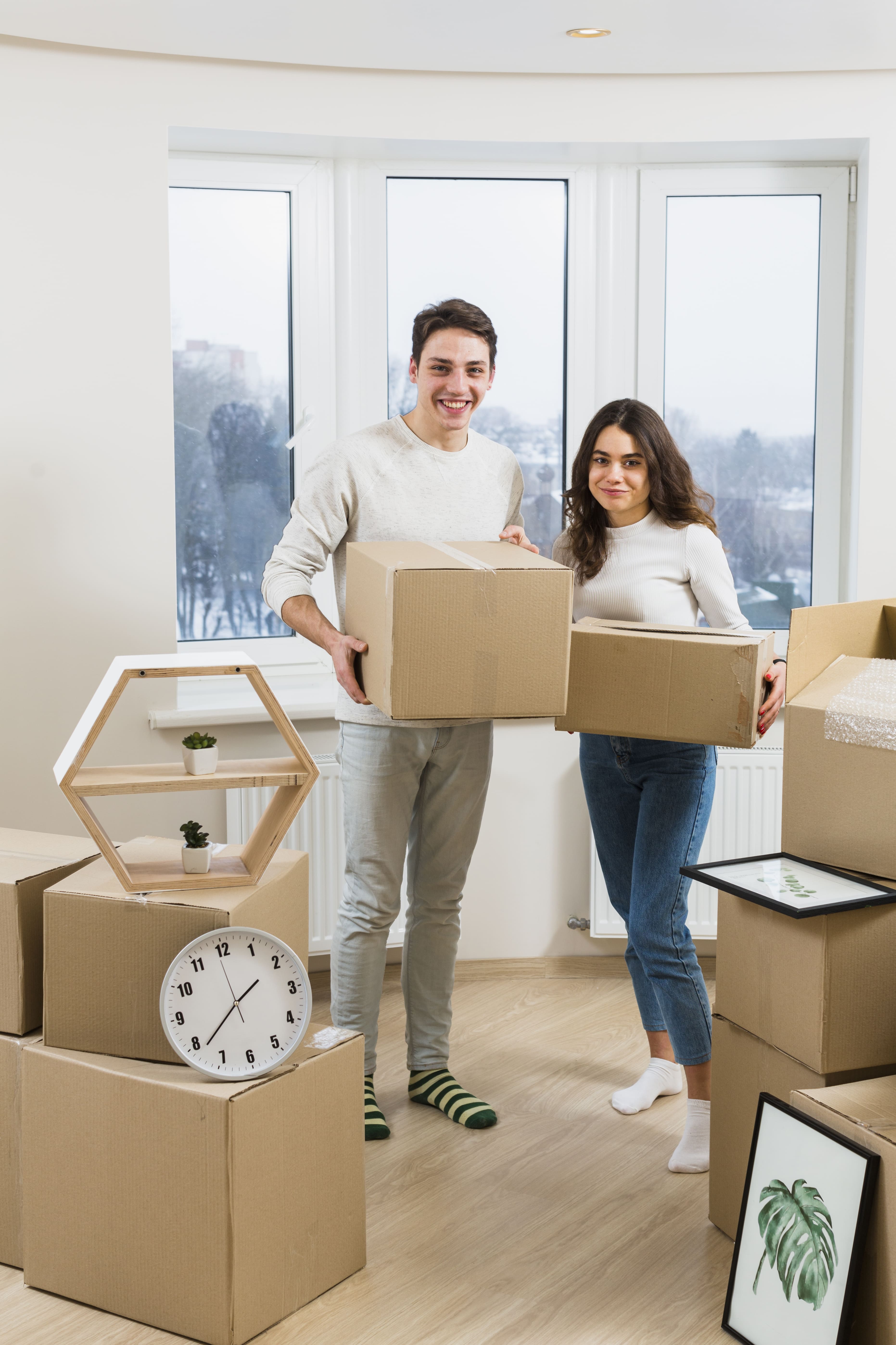 Happy young couple opening boxes in their new home with the help of packers and movers