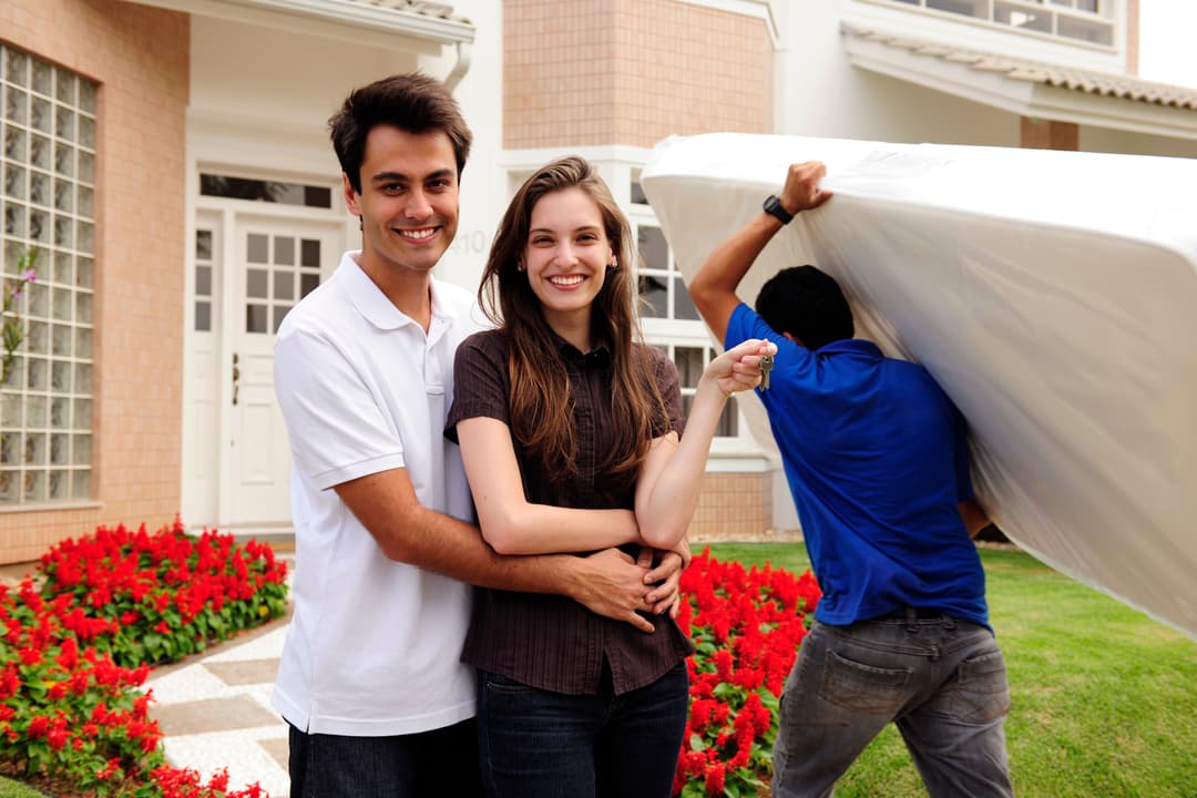 Couple standing in front of their new house, celebrating a successful move into their new home